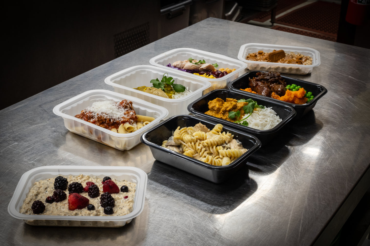 Chef-prepared high-protein ready meals from Fuel & Prep Co arranged on a prep table, including pasta, rice and breakfast meals.